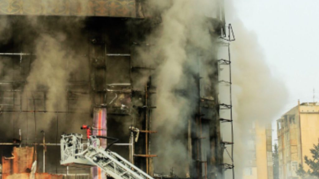 Firefighters battling a large building fire with thick smoke billowing from upper floors