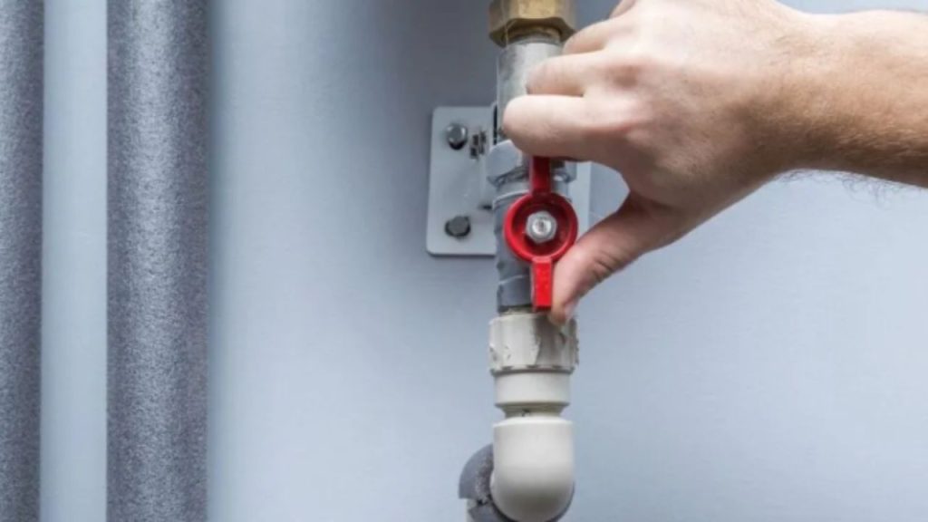 Person operating an emergency water shut-off ball valve to stop the main water supply